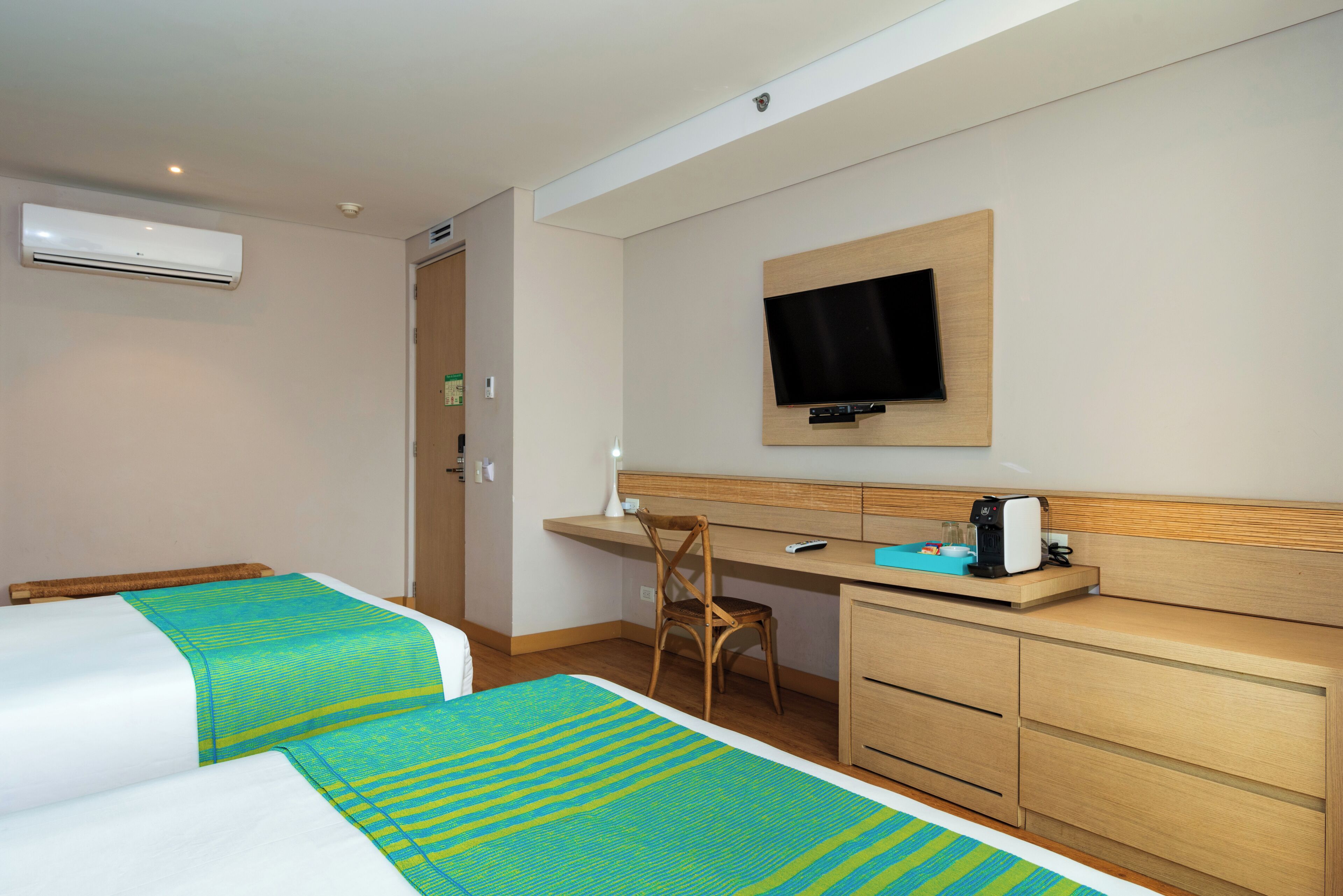 Habitación de hotel con dos camas, un escritorio, una silla, un televisor y un minibar.