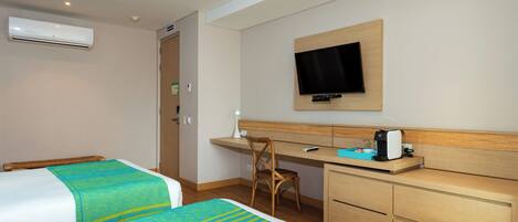 A hotel room with two beds, a desk, a chair, a TV, and a minibar.