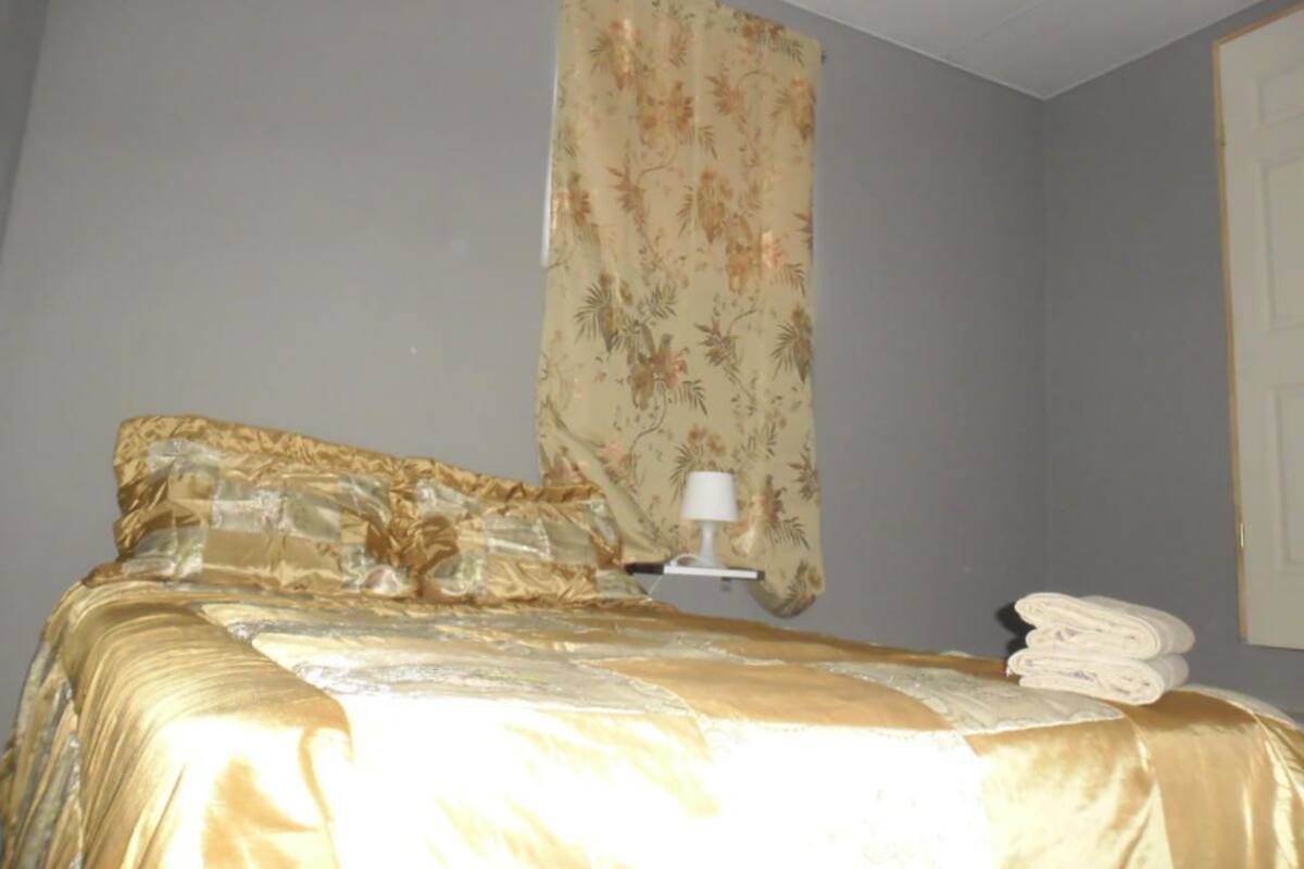 A hotel room with a bed, a nightstand, a lamp, and a window with a floral curtain.