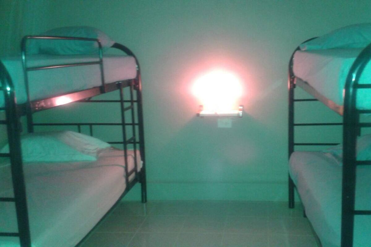 A room with two bunk beds and a single light fixture on the wall.