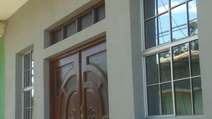 A building with a large wooden double door, a small window to the left, and a larger window to the right. - New Century Hostel (Granada)