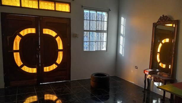A room with a large circular door illuminated from within, a small window with metal bars, a mirror with a decorative frame, and a tiled floor. - New Century Hostel (Granada)