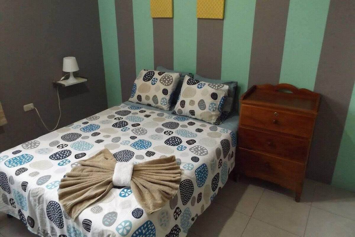 A bedroom with a bed, a nightstand, and a wall-mounted lamp.