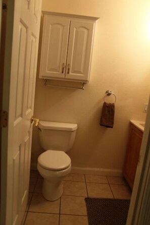 A small bathroom with a toilet, a towel rack, and a cabinet above the toilet.