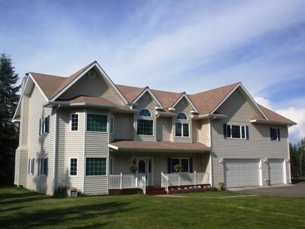 A two-story house with a front porch, a garage, and a well-maintained lawn.