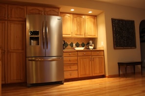 A kitchen with wooden cabinets, a stainless steel refrigerator, and a tiled backsplash.