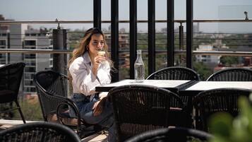 A person seated at an outdoor table with a clear view of the cityscape in the background.