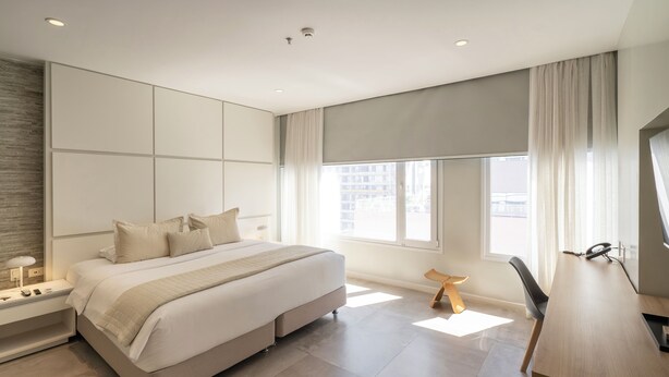 A modern bedroom with a large bed, bedside tables, a desk, and a window. - The Hub Urban Hotel (Asunción)