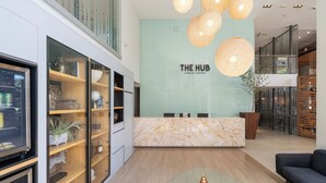 A reception area with a marble counter, glass display cases, a modern sofa, and a glass coffee table. - The Hub Urban Hotel (Asunción)