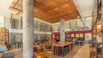 A spacious indoor area with wooden tables and chairs, large columns with floral patterns, and a bar area with seating.