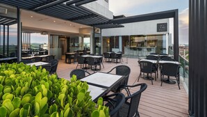 A rooftop terrace with outdoor seating, a bar, and a view of the city. - The Hub Urban Hotel (Asunción)