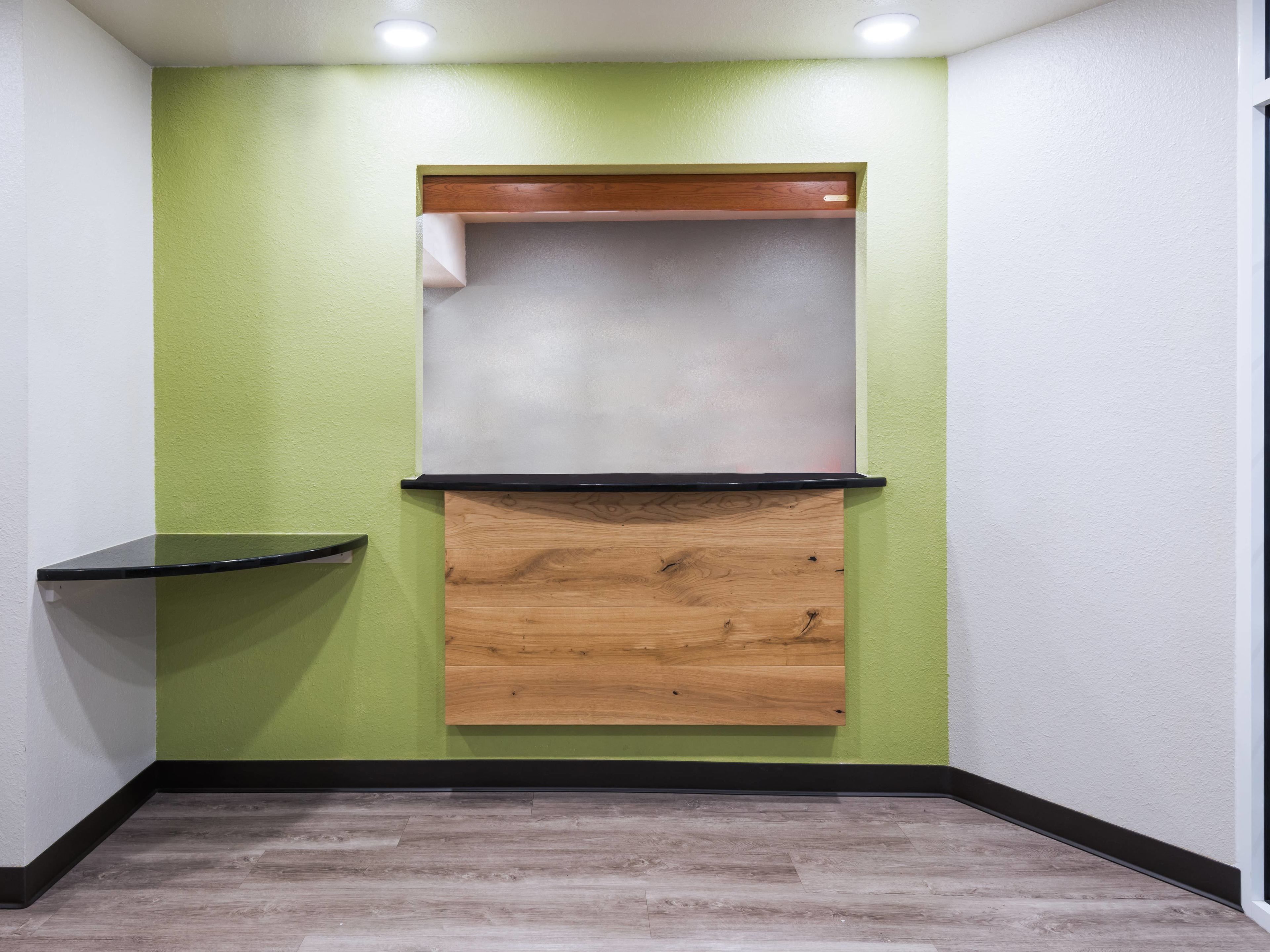 Ein Eckzimmer mit grüner Wand, einer Holzvertäfelung, einer schwarzen Arbeitsplatte und einem weißen Regal.