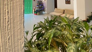 Una sala de estar con una puerta verde, un árbol de Navidad y un sofá color beige.