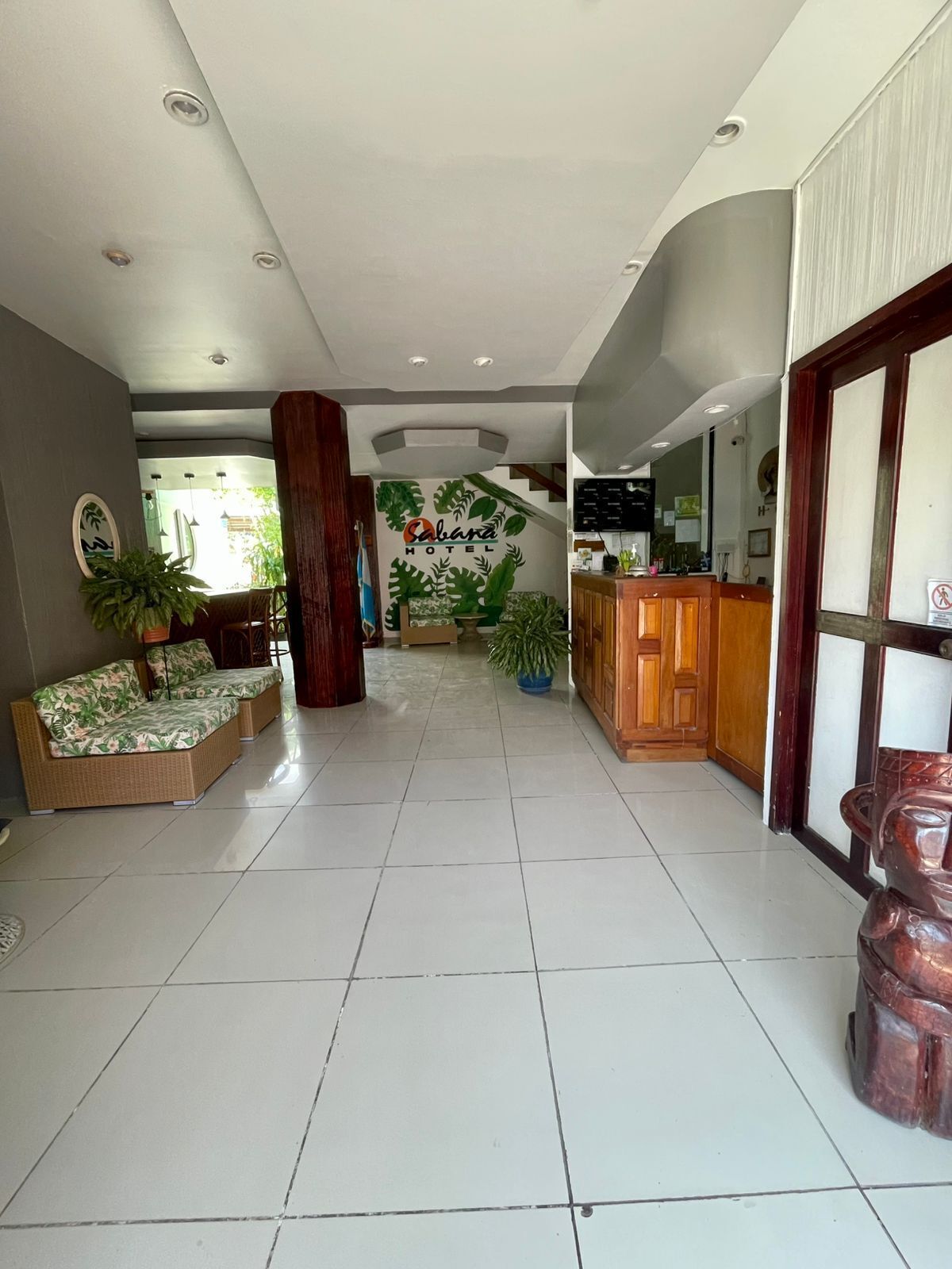 Un vestíbulo de hotel con una recepción, una escalera y una zona de estar con sofás.