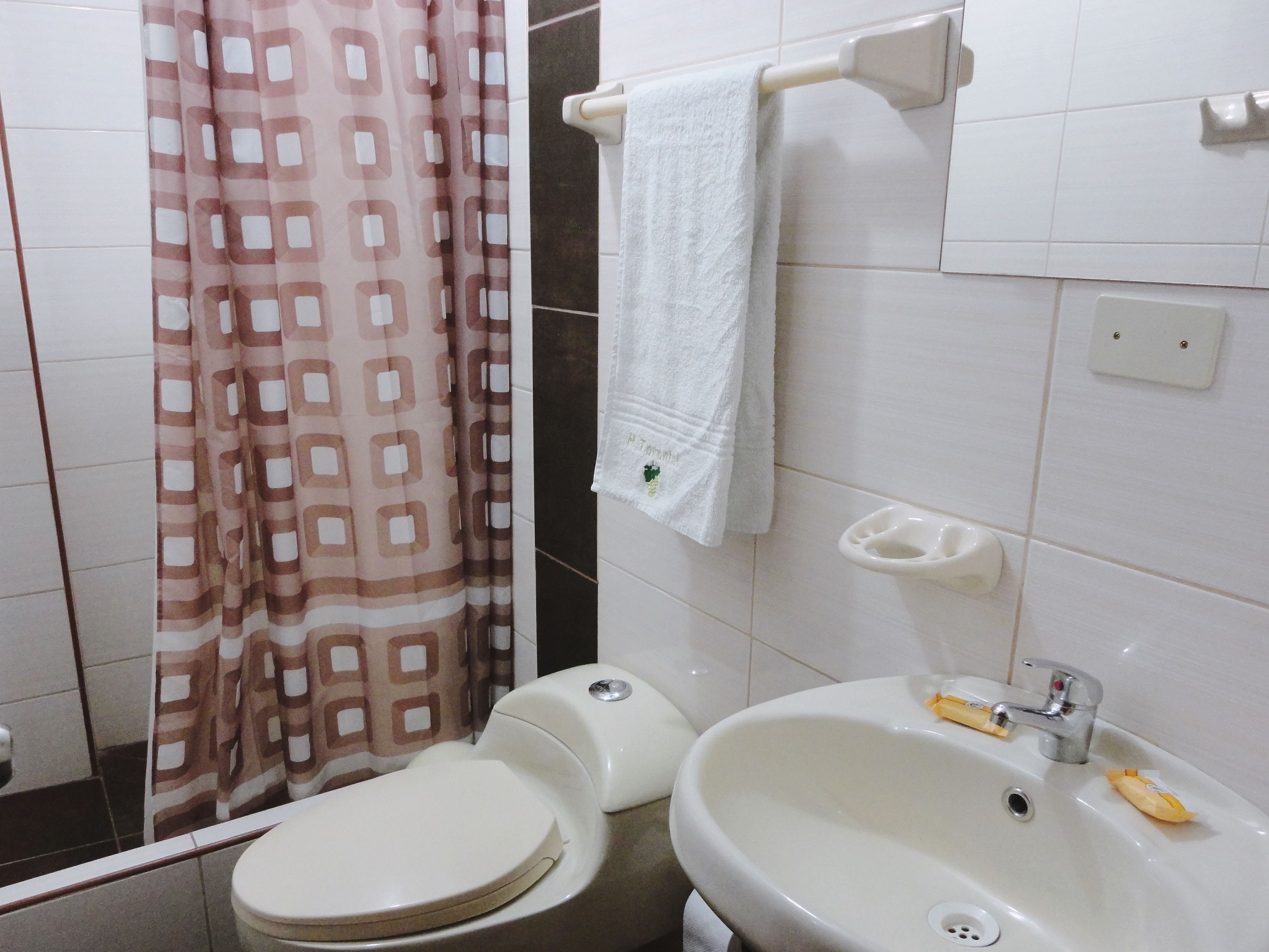 Baño con inodoro, lavamanos y cortina de ducha.