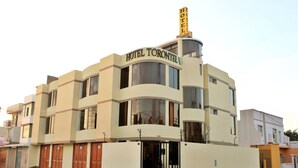 Un hôtel à plusieurs étages, doté d’une façade incurvée, de grandes fenêtres et d’une enseigne bien visible indiquant « HÔTEL TORONTELLY ».