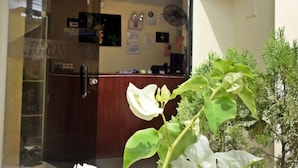 Un espace d’accueil doté d’une porte en verre, d’un comptoir de réception et d’une enseigne avec la lettre « H ».