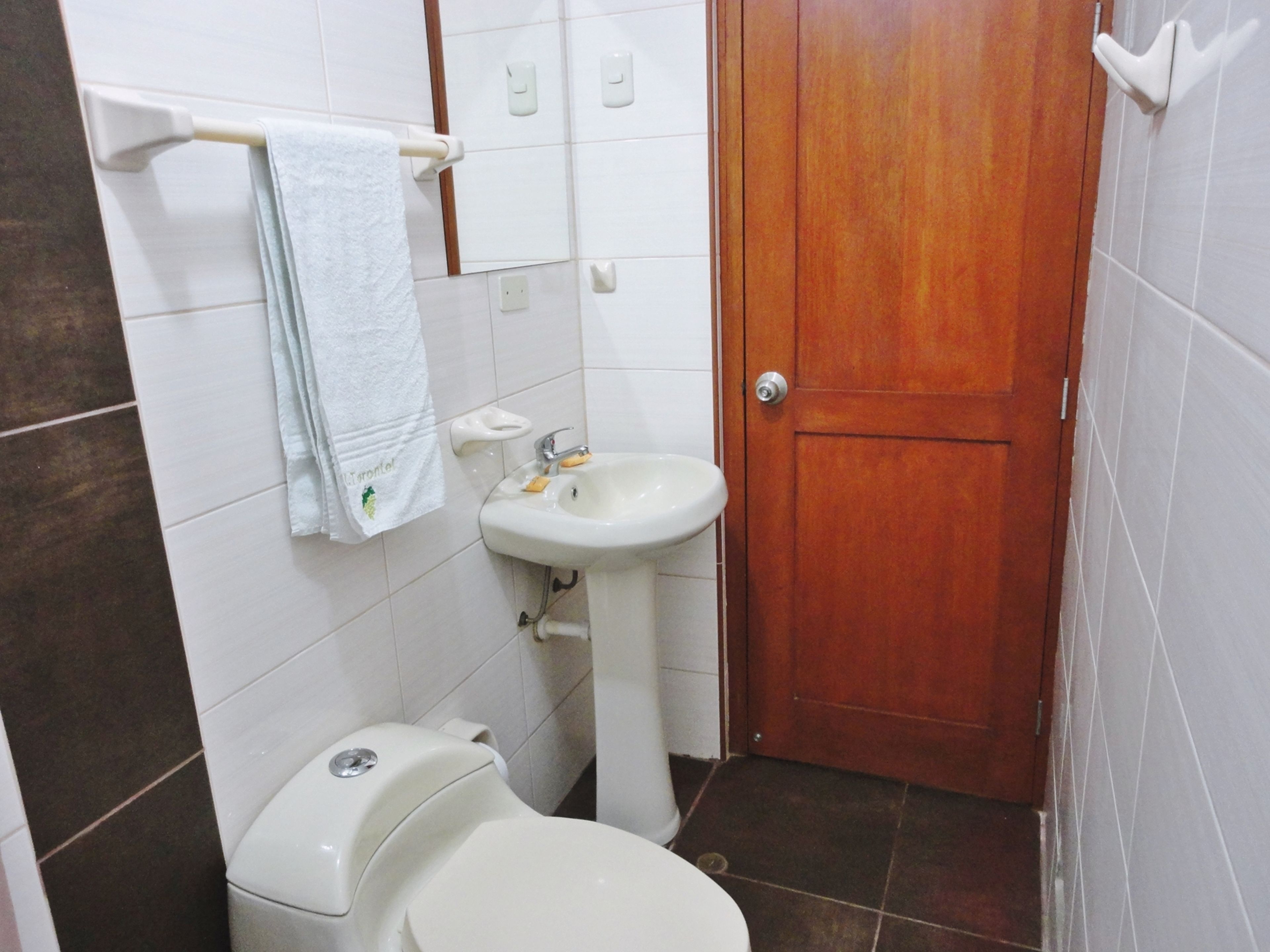 Un baño con inodoro, lavamanos y puerta de madera.