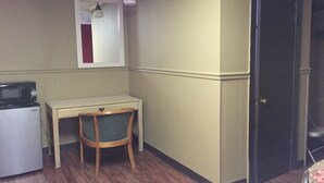 A compact room with a desk, chair, microwave, and a door. - Morgan City Motel (Morgan City)