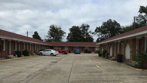 A motel with a central parking area, a row of rooms on either side, and a blue car parked in the middle. - Morgan City Motel (Morgan City)