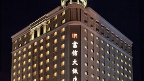 Un hôtel à plusieurs étages, doté d’une enseigne lumineuse et d’une architecture classique.