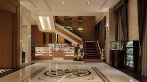 Un hall d’entrée spacieux avec un escalier central, un espace d’accueil et une exposition d’objets.