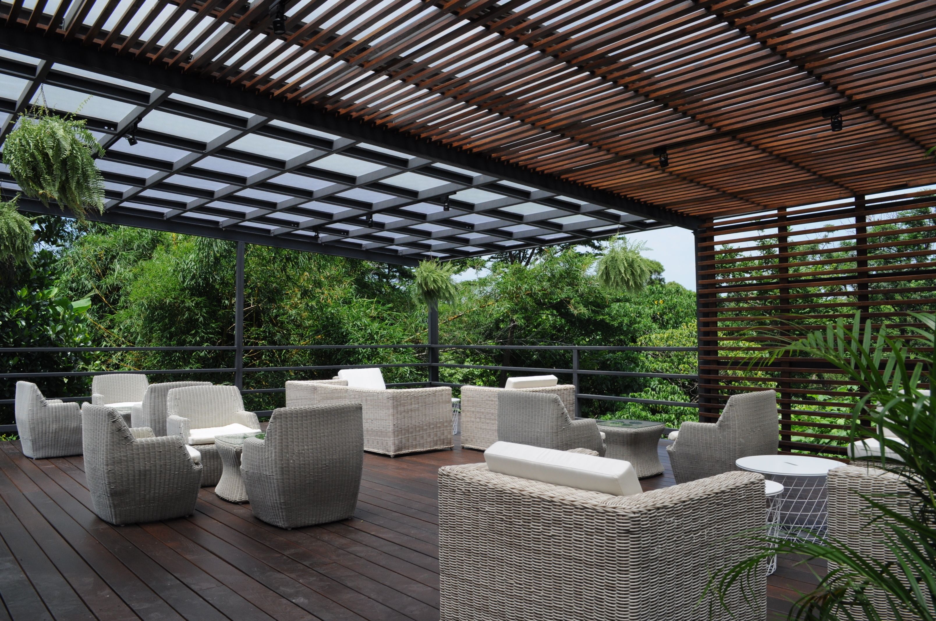 A covered outdoor seating area with wicker furniture and a wooden ceiling.