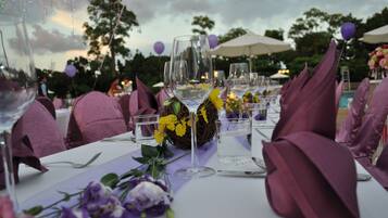 A table set with purple napkins, clear glasses, and yellow flowers.