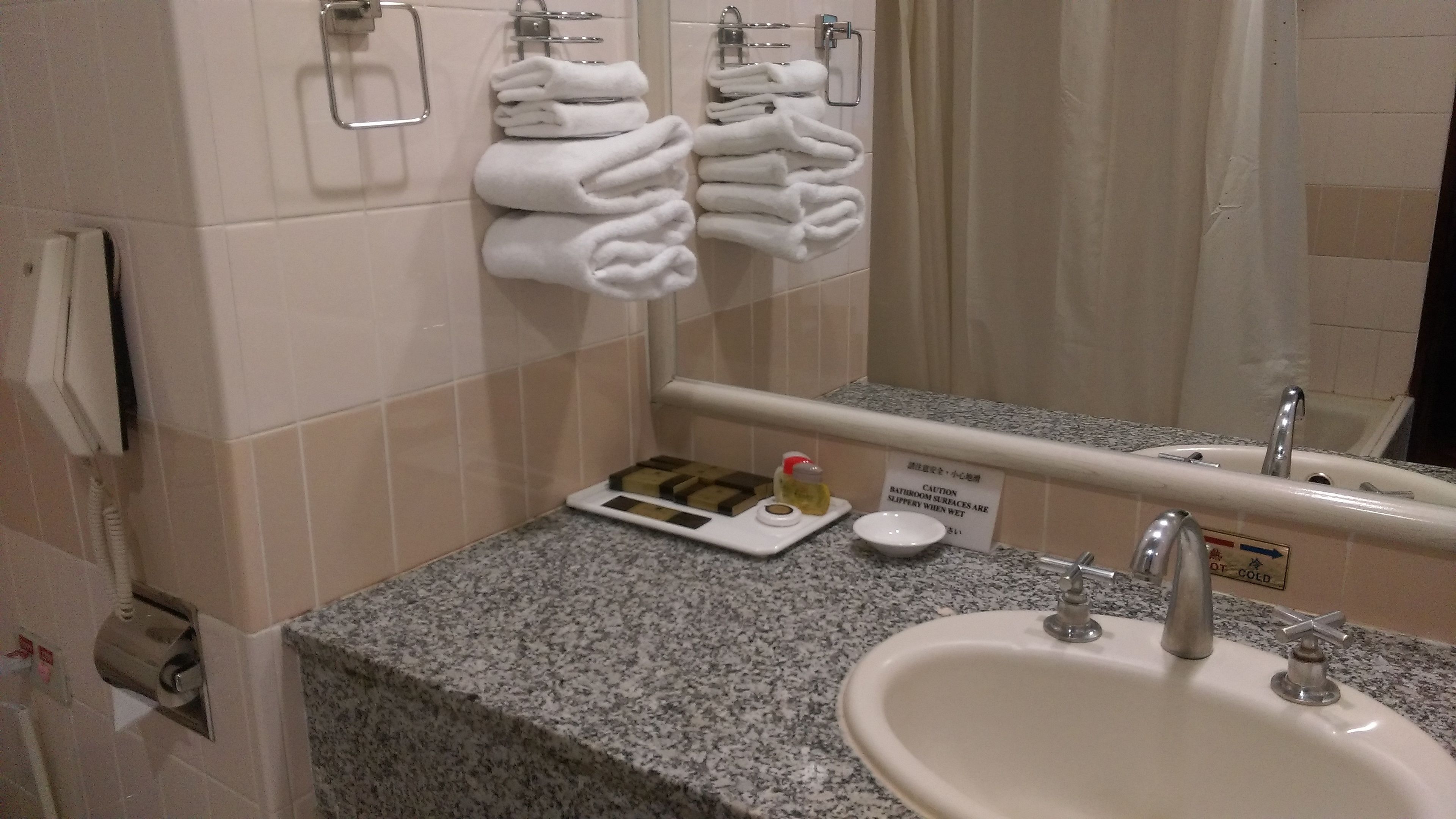 A bathroom with a sink, mirror, towel rack, and toiletries.