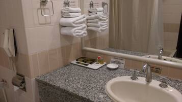 A bathroom with a sink, mirror, towel rack, and toiletries.