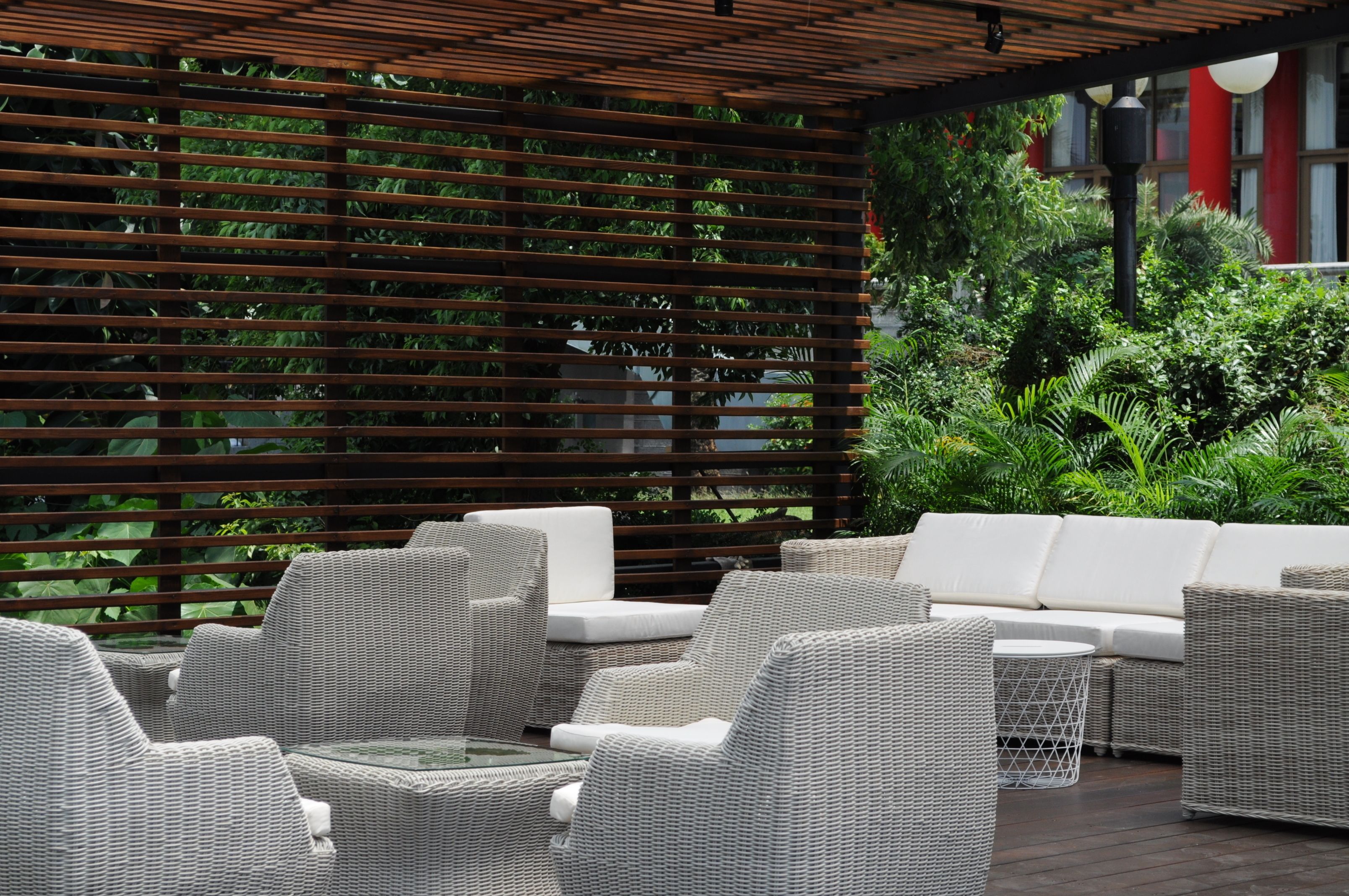 An outdoor seating area with wicker furniture and a wooden pergola.
