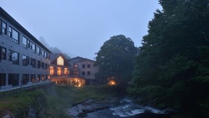A riverside hotel with modern architecture, a visible river, and surrounding greenery. - La Vista Akangawa - Adults only (Kushiro)