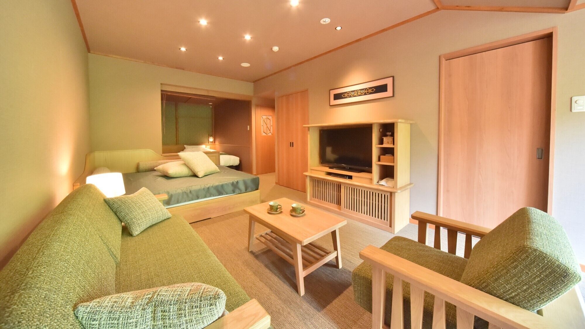 A room with a bed, a sofa, a TV, and a small table.