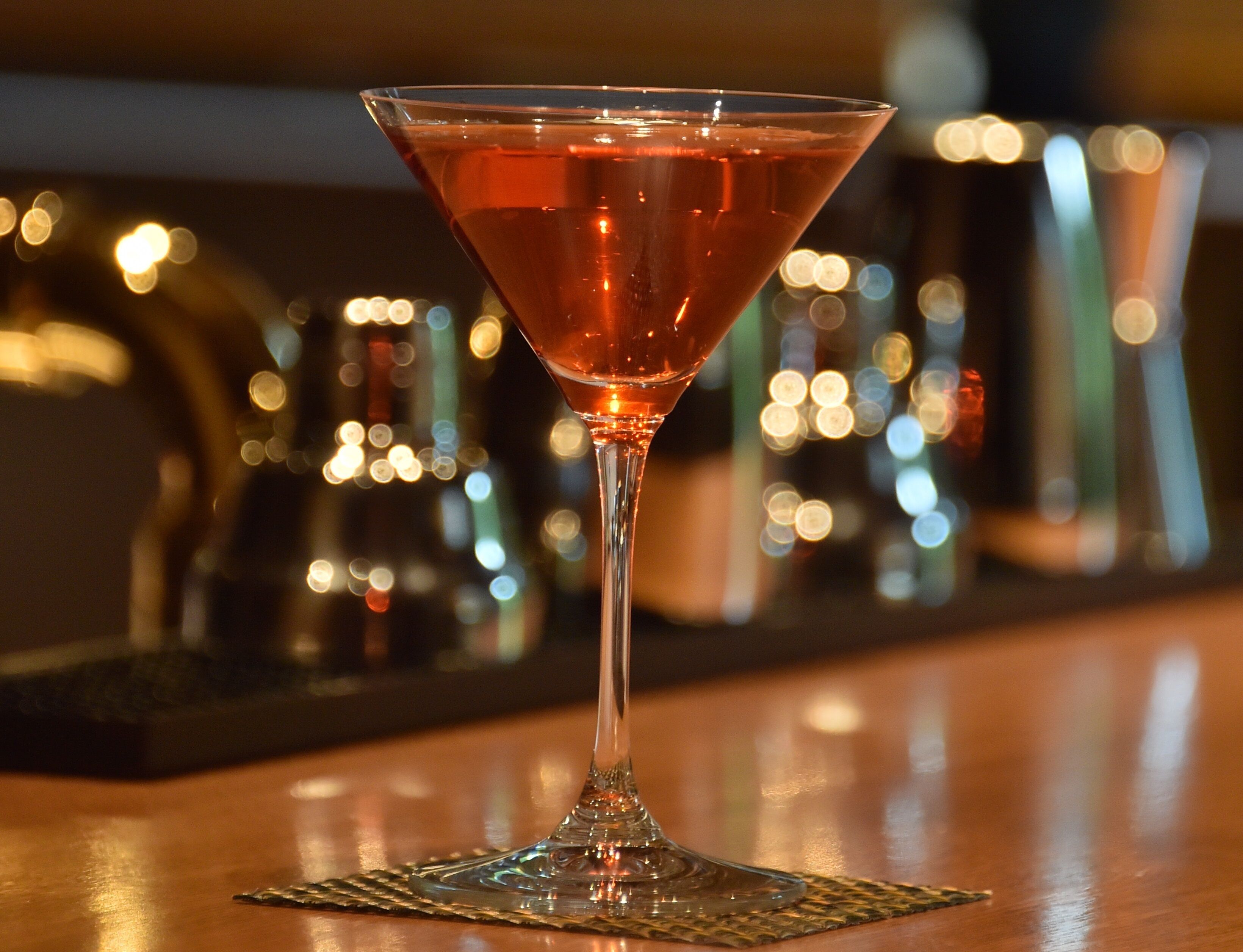 A martini glass on a bar mat.