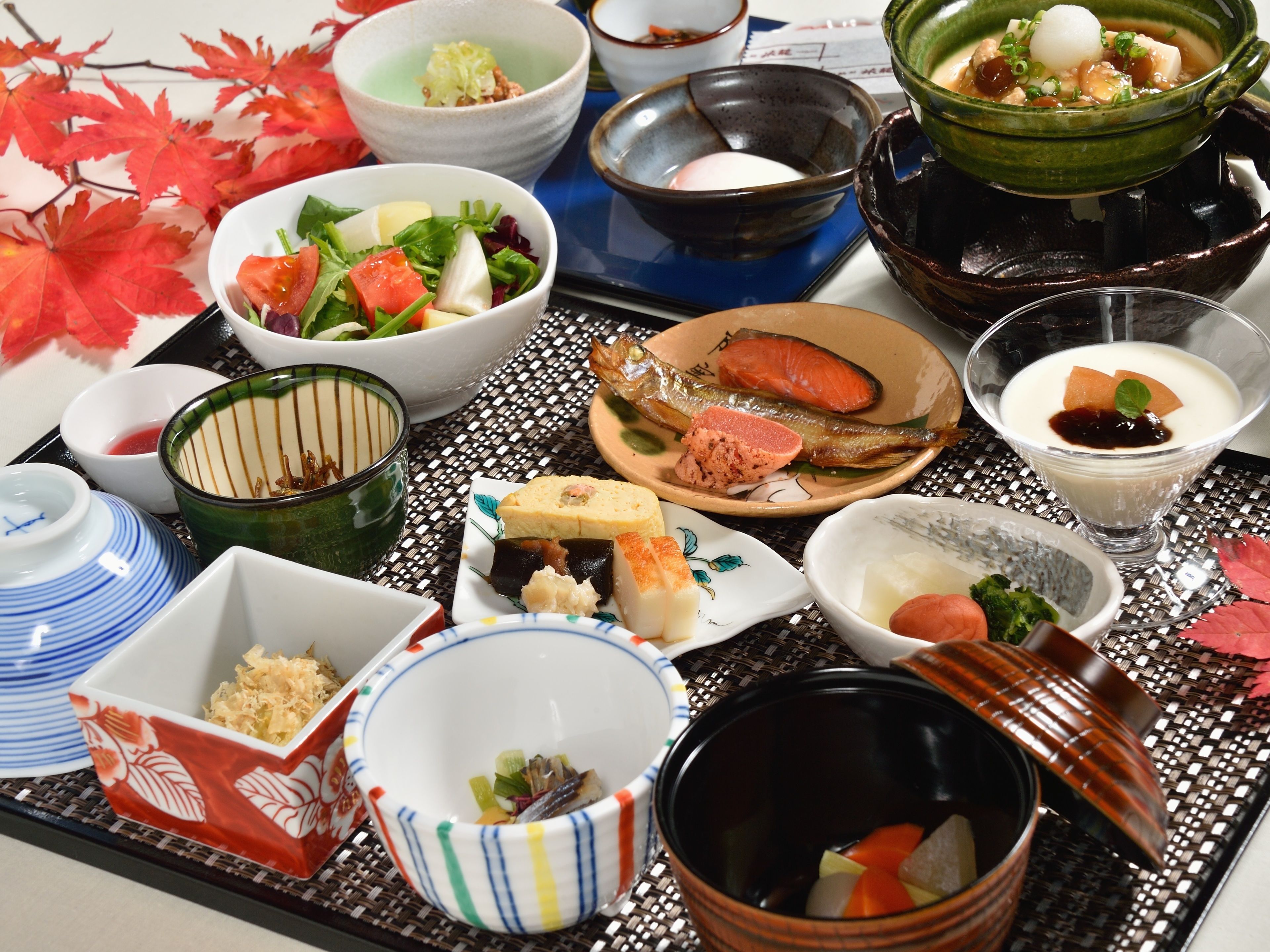 Una variedad de platos japoneses en una bandeja, incluyendo sushi, sashimi y un tazón de sopa.