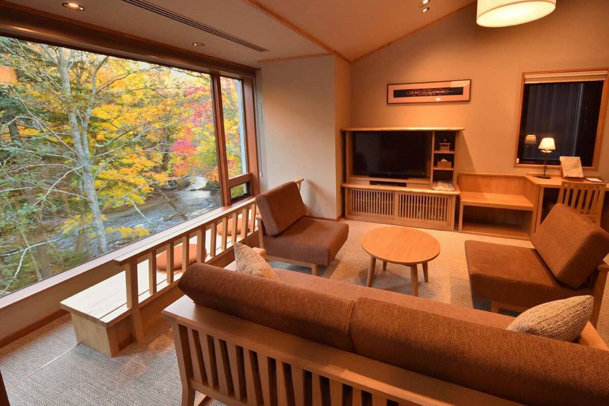 A cozy living room with a large window, a flat-screen TV, and a comfortable seating area.