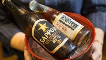 Una persona sosteniendo una botella de cerveza Sapporo en un cubo.