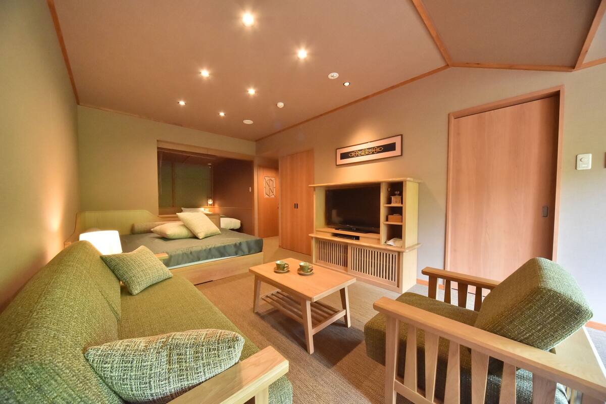 A cozy living room with a sofa, armchair, and TV stand.