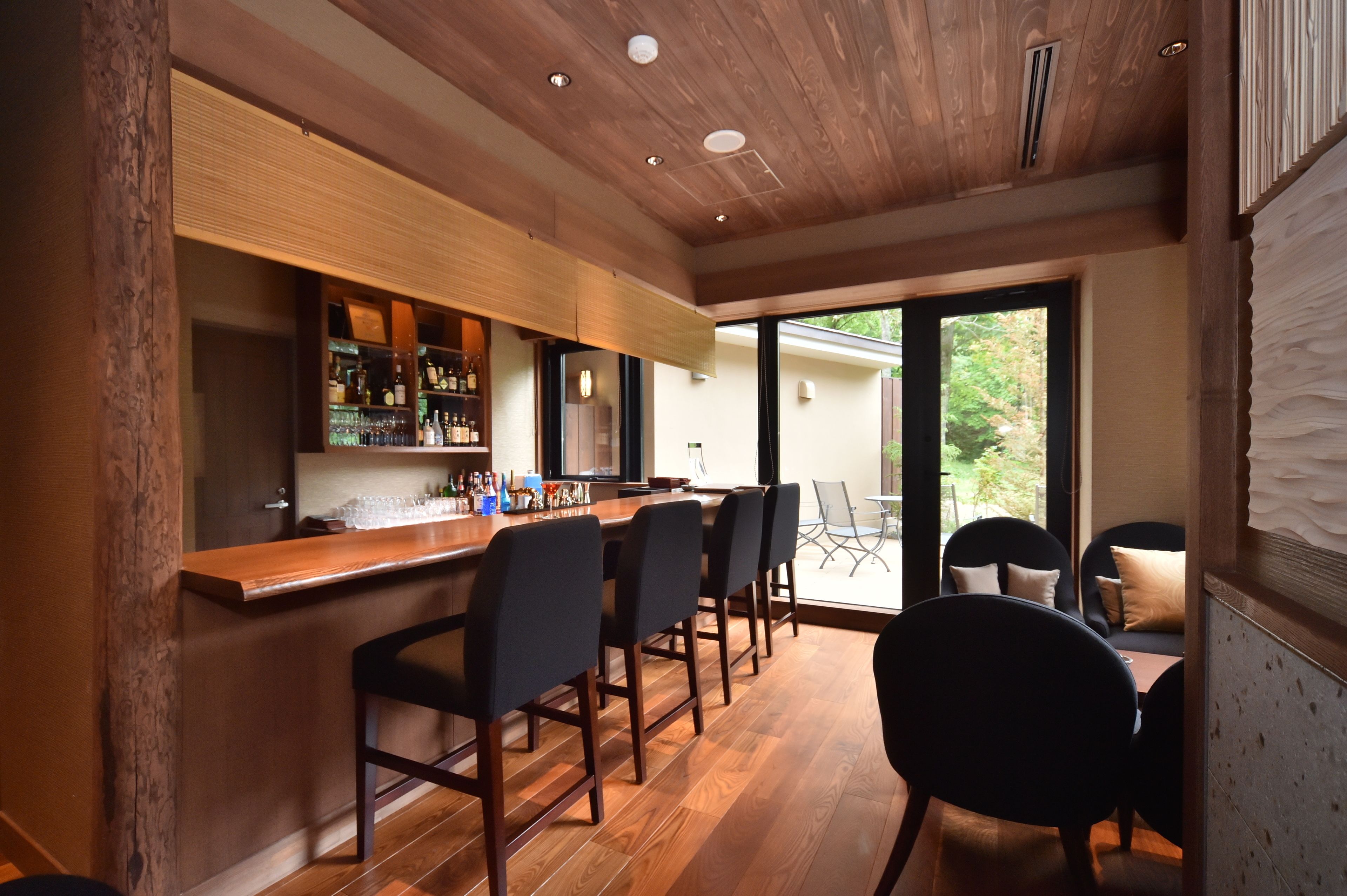 Une cuisine moderne dotée d’un plan de travail en bois et d’un coin bar, aménagé avec des tabourets de bar et un porte-bouteilles.