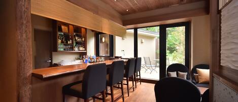 Une cuisine moderne dotée d’un plan de travail en bois et d’un coin bar, aménagé avec des tabourets de bar et un porte-bouteilles.