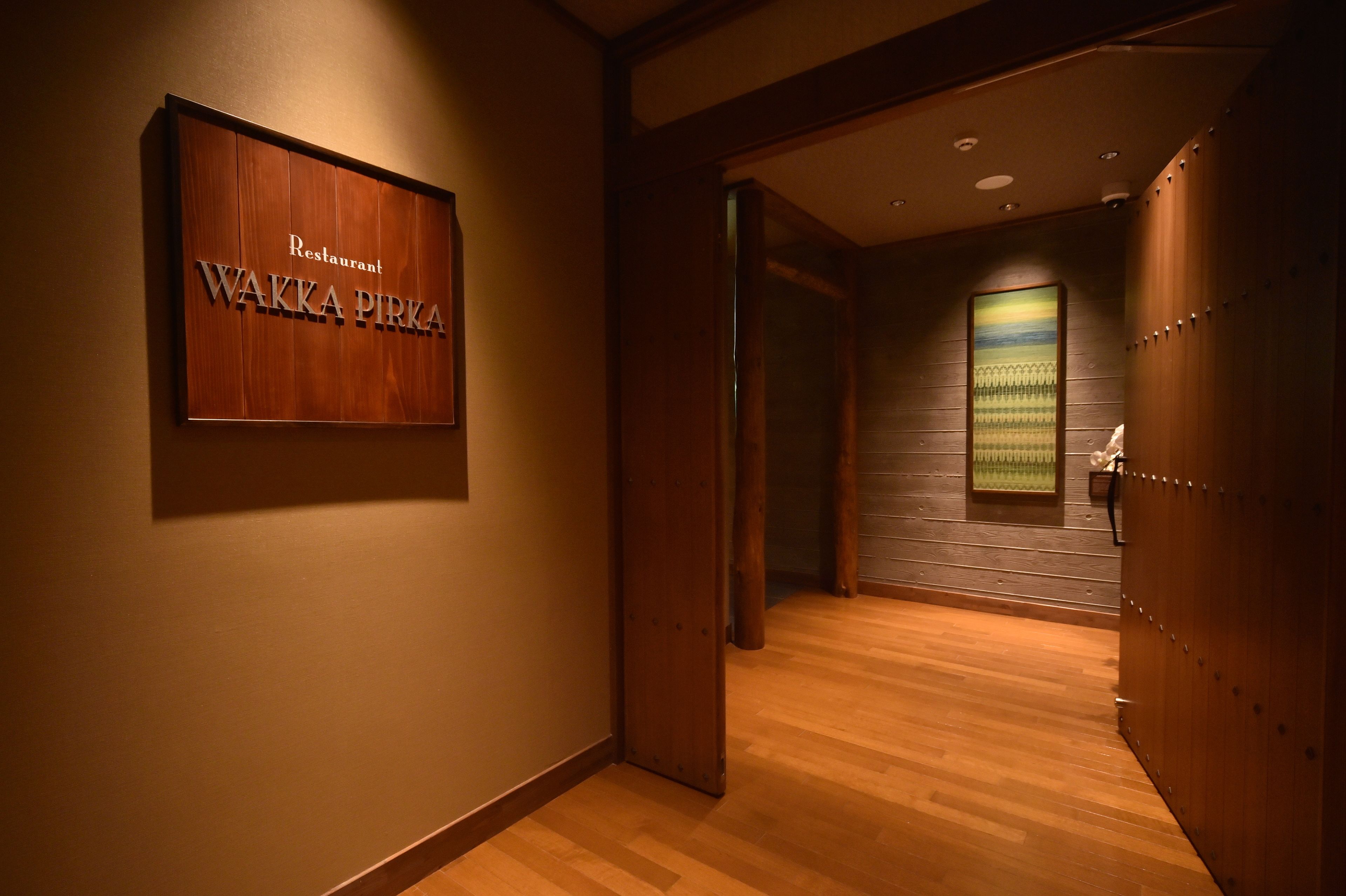 A hallway with a wooden floor and a sign that reads "WAKKA PIRKA Restaurant".
