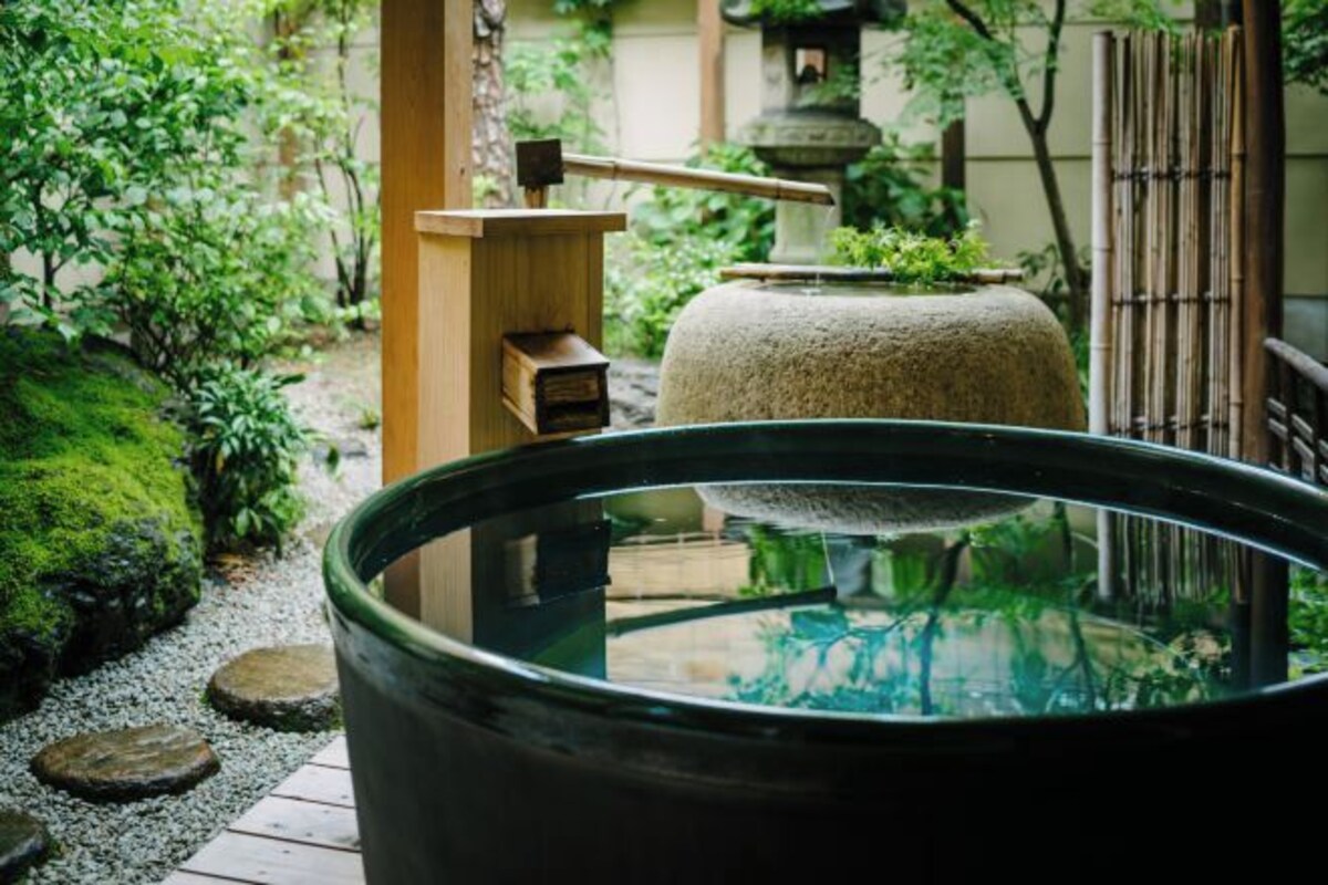 Perinteinen japanilainen puutarha, jossa on kivilyhty, puinen rakennelma ja suuri kiviallas.