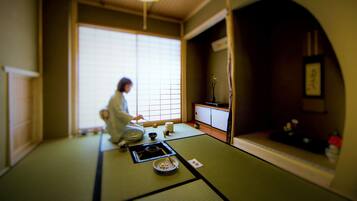 A traditional Japanese room with tatami flooring, a low table with a tea set, and a sliding door.