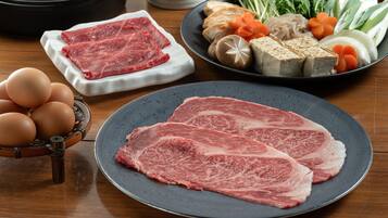 A dining table with various food items including raw meat, eggs, vegetables, and tofu.