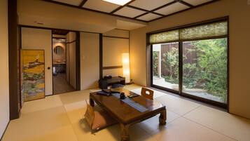 A traditional Japanese room with tatami flooring, a low wooden table, and sliding doors leading to a bathroom.