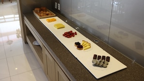 Un mostrador de buffet con diversos postres, incluyendo pasteles, fruta y bollería.