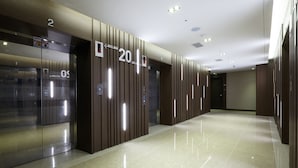 Un pasillo moderno de hotel con piso pulido, paneles de madera y números de ascensor que señalan los pisos del 2 al 4.