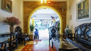 Un hall d’entrée avec une arche en briques, des meubles décoratifs et une vue sur l’espace boutique.