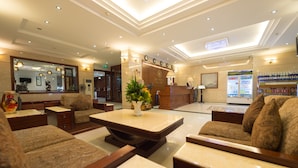 A hotel lobby with seating areas, a reception desk, and a beverage refrigerator. - Iris Hotel Danang (Da Nang)