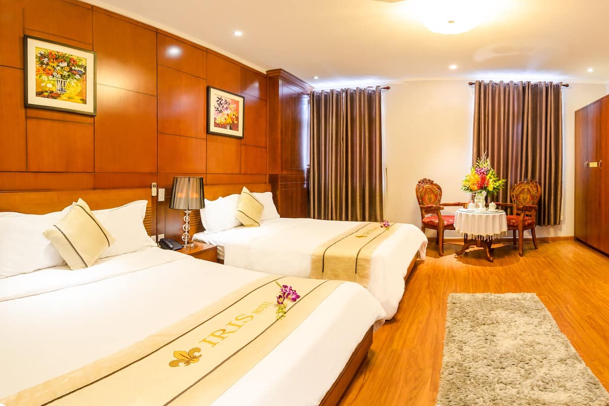 Habitación de hotel con dos camas, un escritorio, una silla, un televisor y una mesa de comedor con sillas.